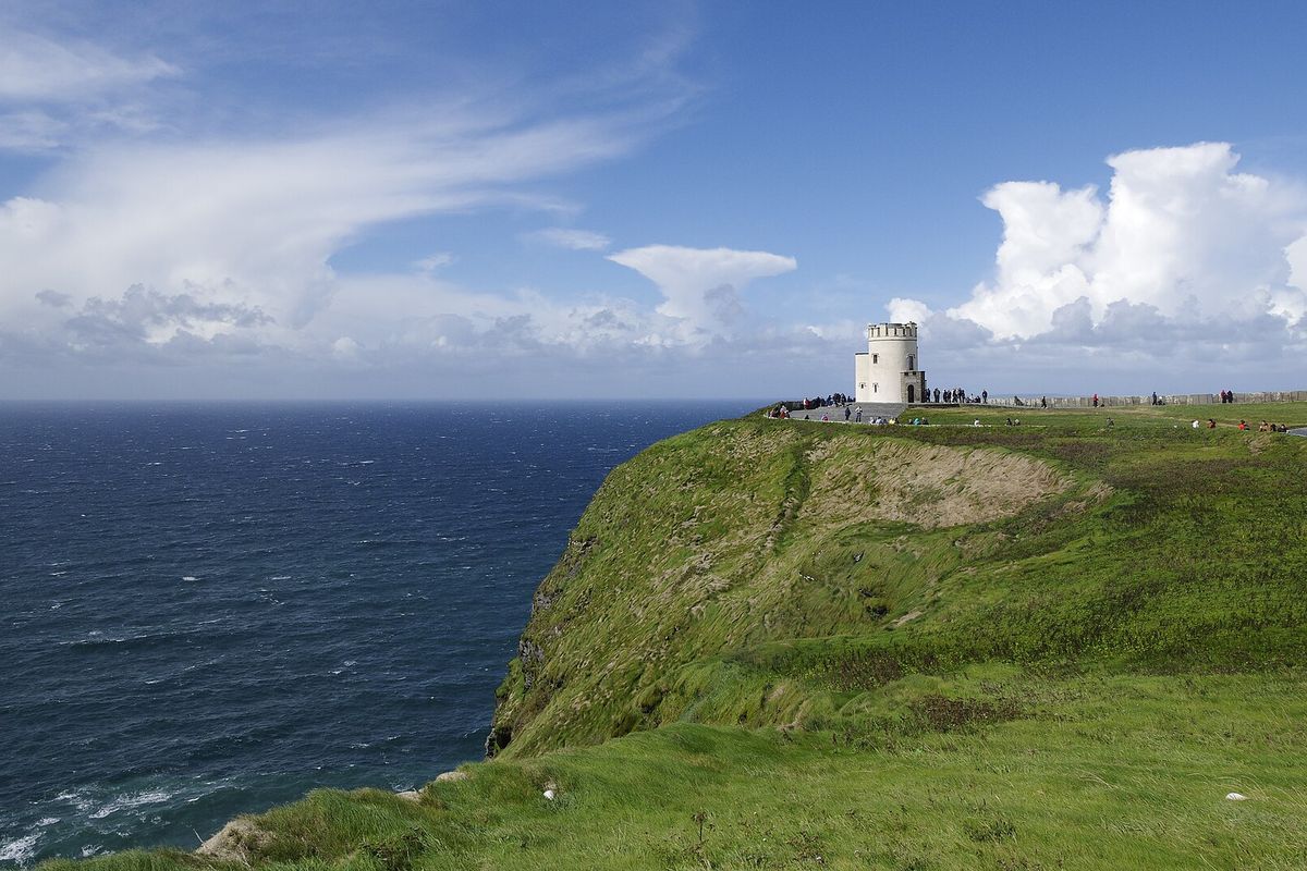 Green clifftops falling to the Atlantic at the Cliffs of Moher, with O'Brien's Tower on the headland