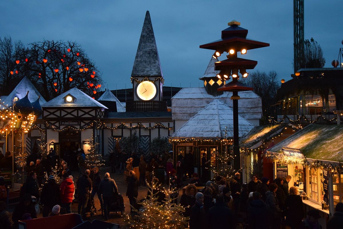 Wooden stalls strung with lights at the Christmas market in Tivoli Gardens, Copenhagen, at blue hour